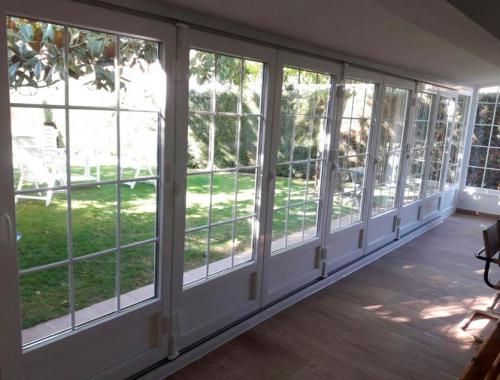 Cerramiento de porche con una corredera plegable de PVC con barrotillo. 