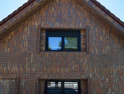 Fachada lateral de una casa con ventanas de PVC en color negro. 