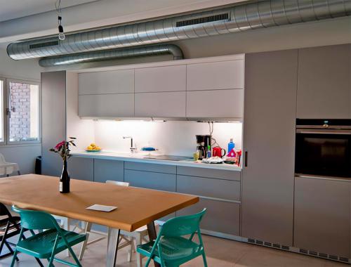 Cocina en tonos grisáceos con un toque de color que integra un excelente diseño y la utilidad del espacio para favorecer la comodidad de los clientes. 