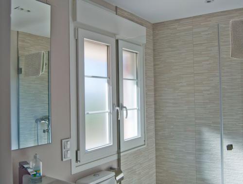 Ventana de PVC con cristal translúcido y persiana motorizada en baño.