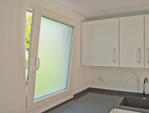 Ventana oscilobatiente de PVC con vidrio translúcido en cocina.