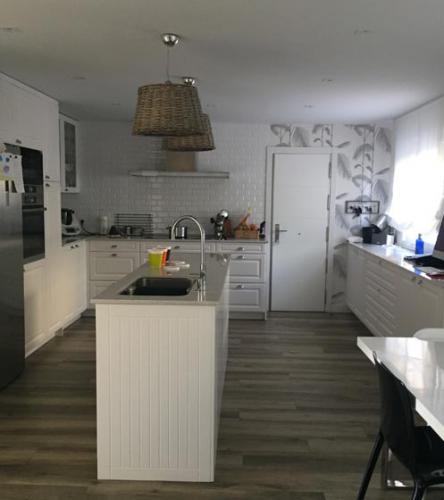 Cocina en tono blanco con isla central diseñada de forma personalizada según las exigencias del cliente.